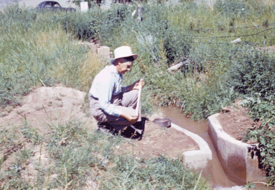 Dr. Parshall reading the water level in a concrete Parshall flume stilling well