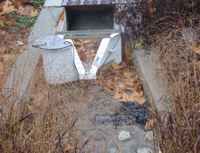 h flume measuring storm water with leaves collecting upstream
