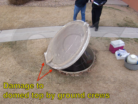 Too shallow Tracom domed top packaged metering manhole.  Damage around the top and at the hinge by ground crews indicated.