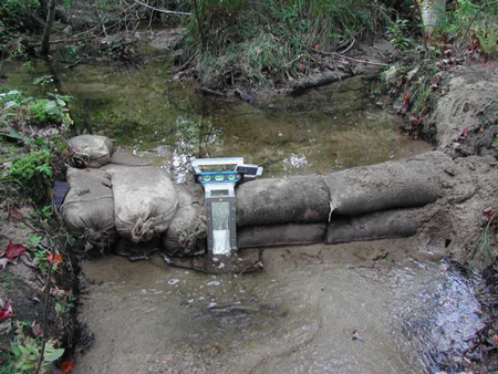 sand bags serving as temporary wing walls for a portable USGS Parshall flume measuring stream flow